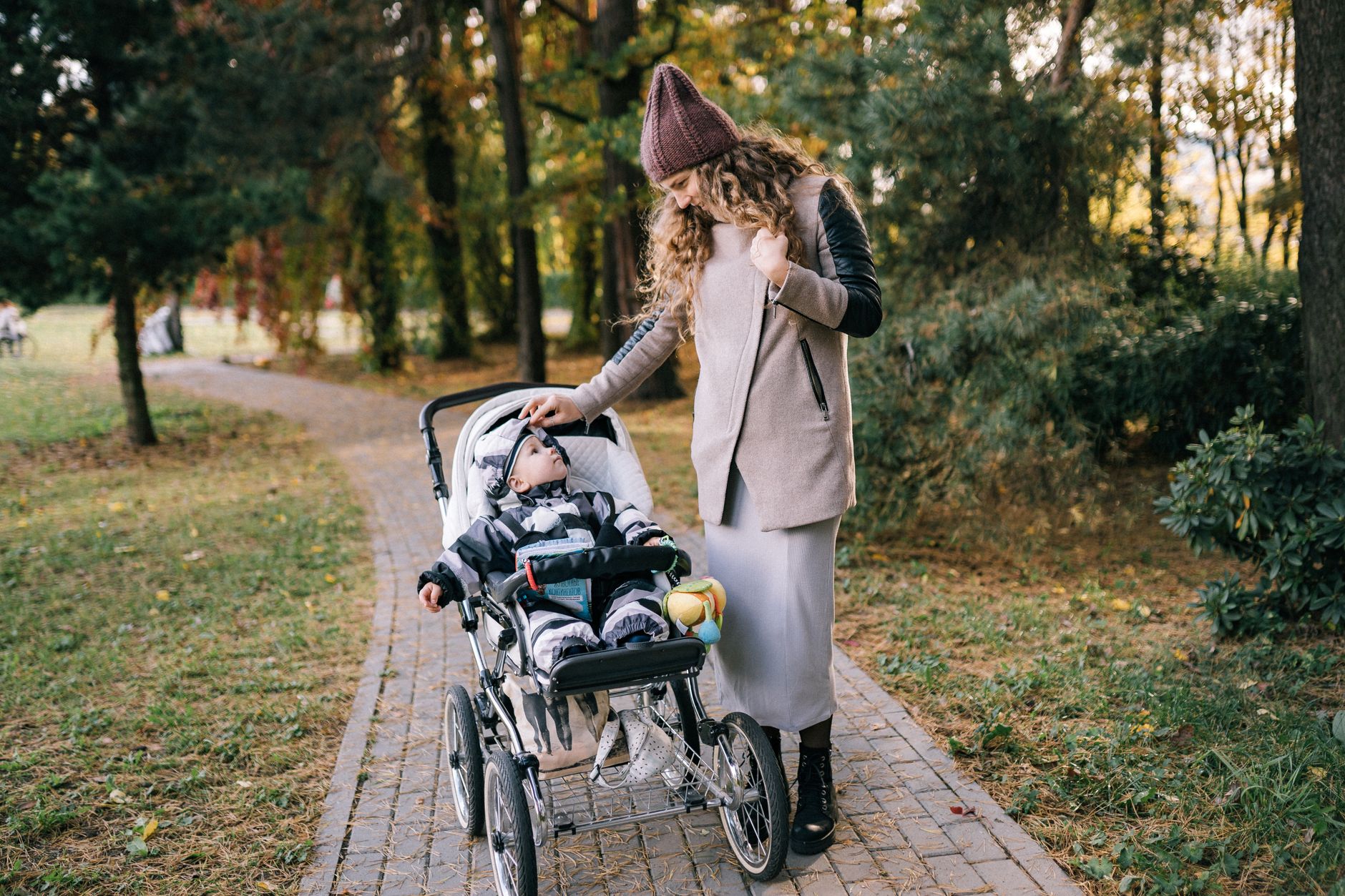 mother walking stroller park path